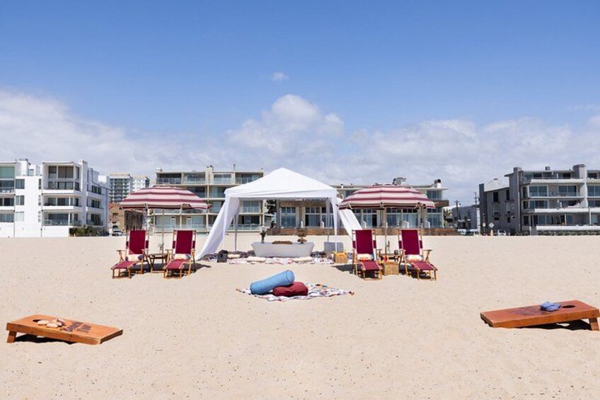 A beach with a white tent, red and white striped umbrellas, and lounge chairs. 1