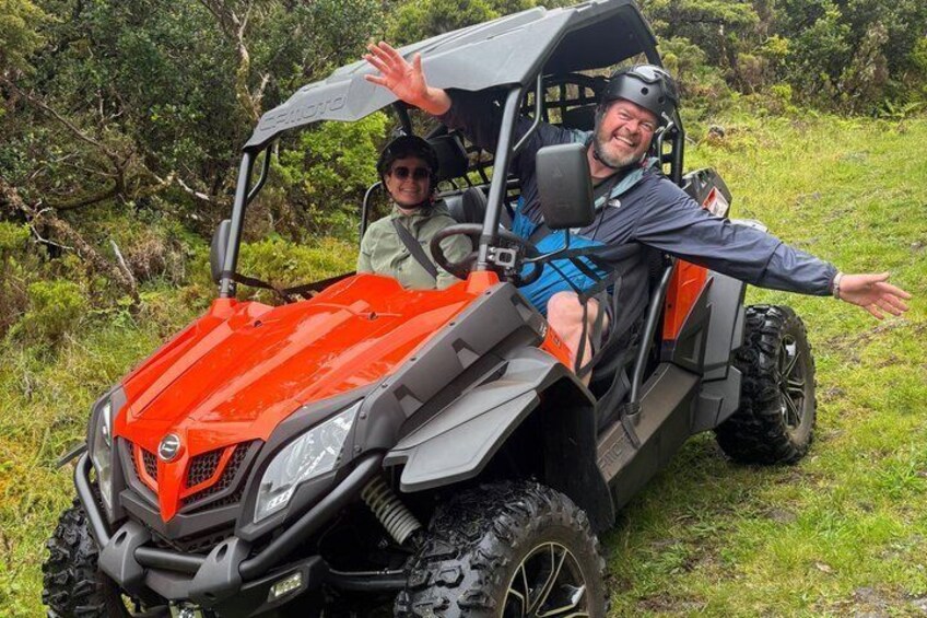 A red off-road vehicle with a person driving and another person sitting beside it. 3