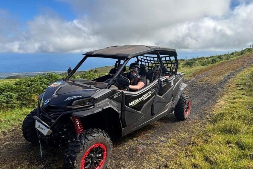 A black ATV with red rims on a dirt road with a coastal view. 5