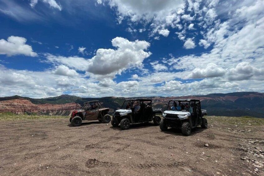 Three off-road vehicles parked on a dirt road with a mountainous landscape in the background. 4