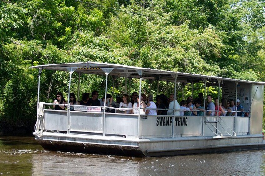 A boat with people on it, surrounded by water and greenery. 1
