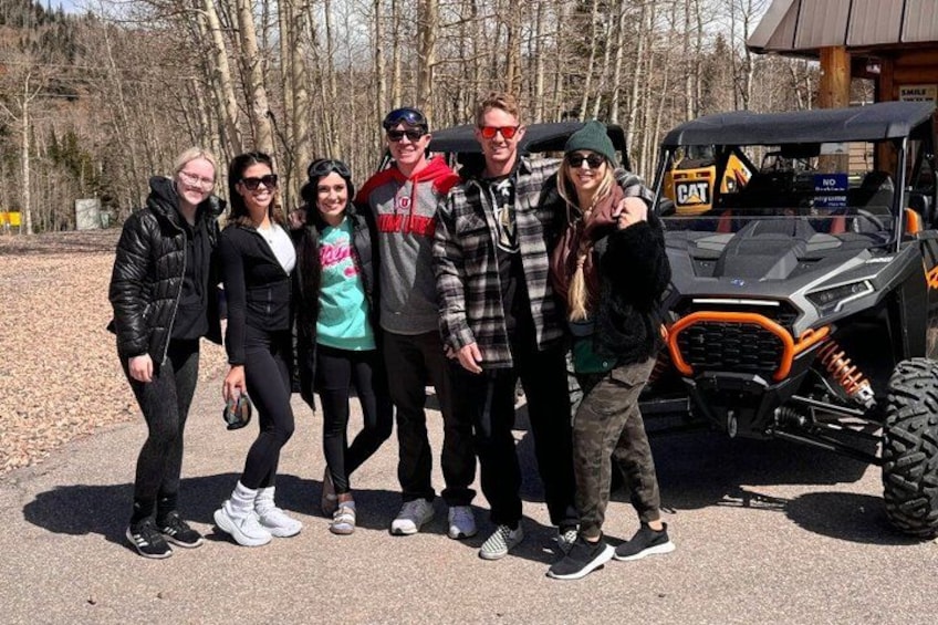 A group of people standing in front of a vehicle with a logo on the front. 2