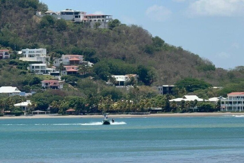 A coastal area with buildings on a hillside, a body of water, and a boat. 2