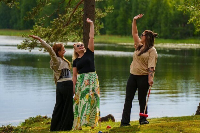 Three people standing by a lake with trees in the background. 1