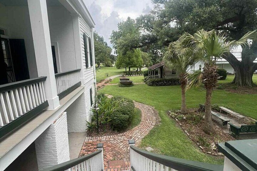 A white building with a balcony, a brick pathway, a palm tree, and a well-maintained lawn. 4