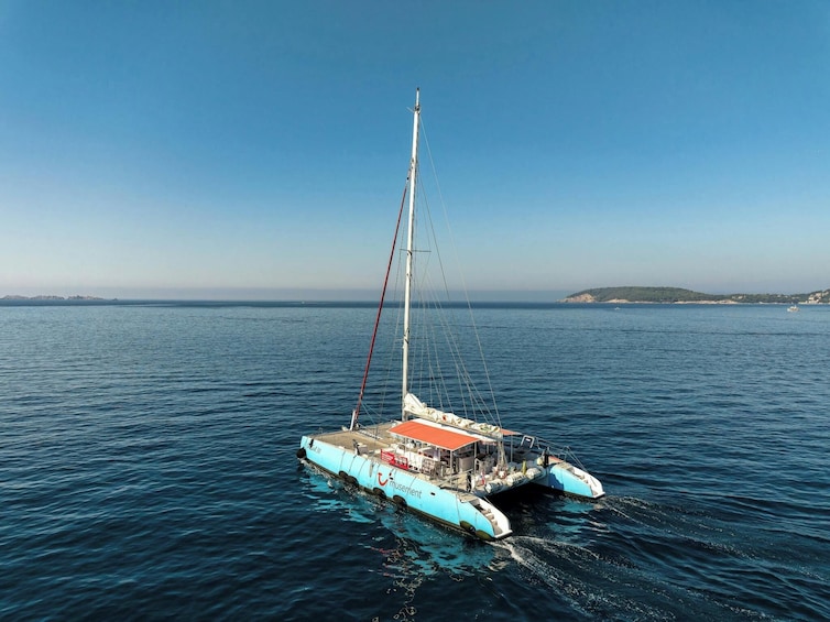 Un catamaran bleu et blanc, doté d’une voile, qui flotte sur des eaux calmes. 1