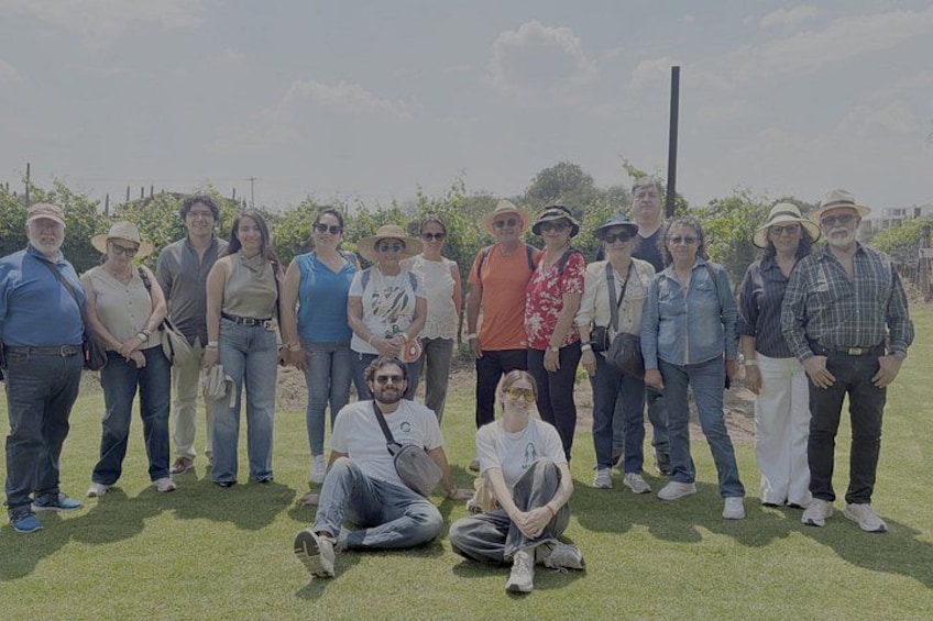 A group of people standing and sitting on grass in an outdoor setting. 1