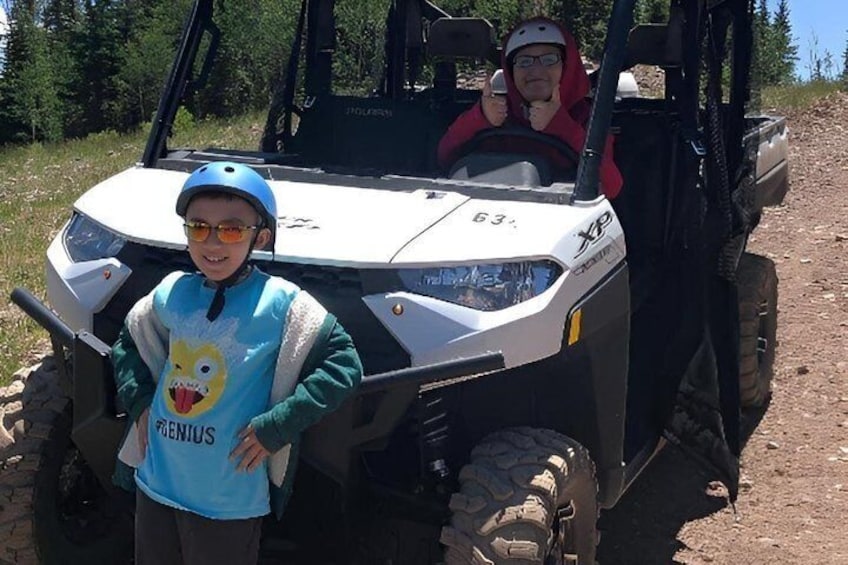 A person in a blue shirt with a cartoon character and another in a red shirt sitting in a white ATV. 1