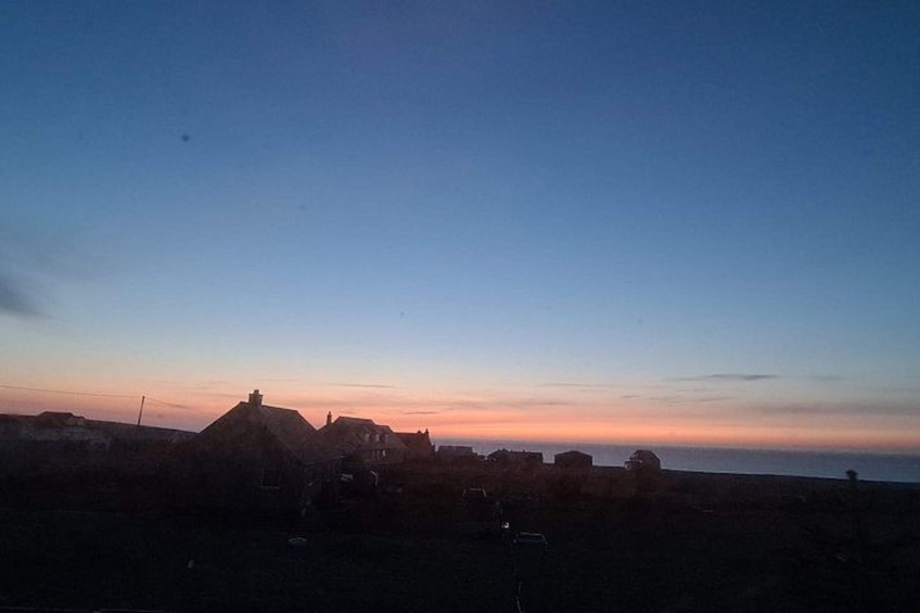 A rural landscape at dusk with a clear sky, a few buildings, and a distant horizon. 4