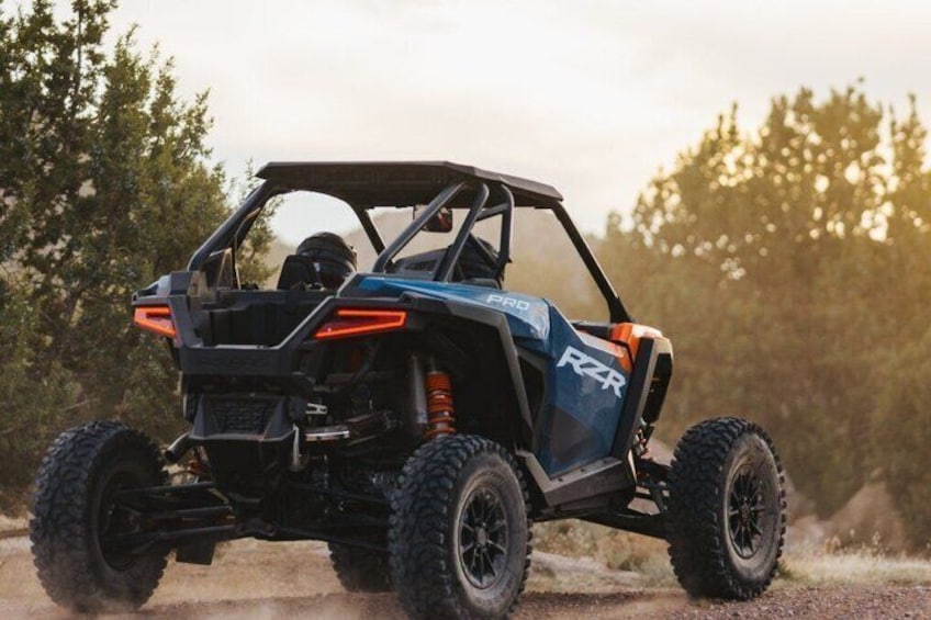 A blue and black off-road vehicle with large tires, a roof, and a visible logo on the side. 3