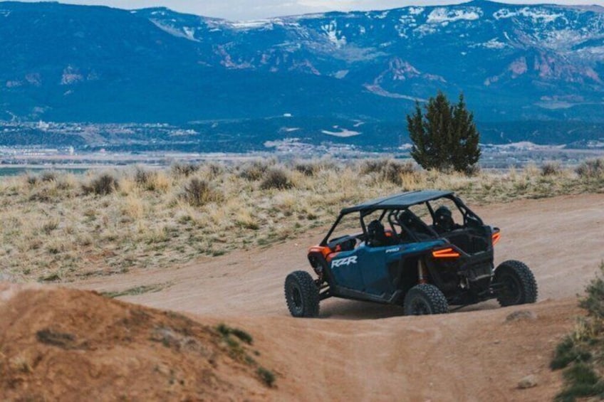 A vehicle on a dirt road with mountains in the background. 2