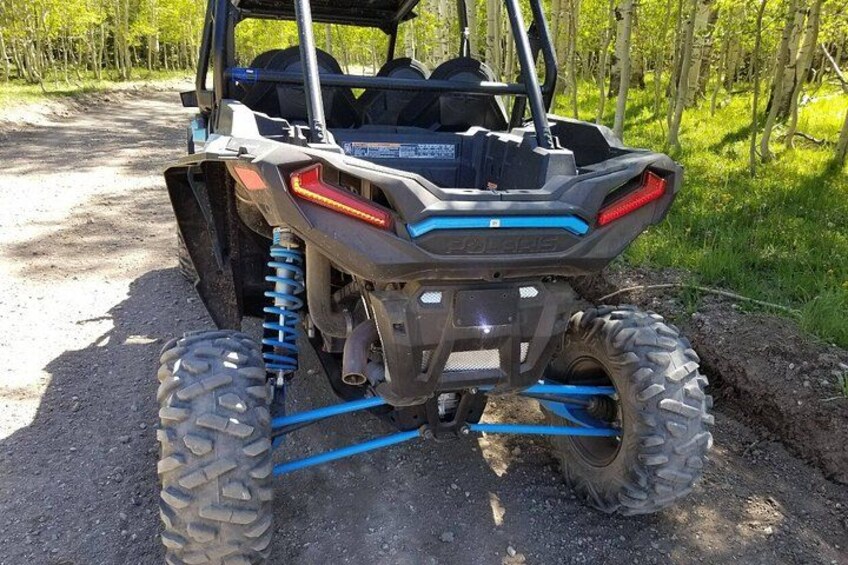 A Polaris ATV parked on a dirt path with a forest in the background. 3