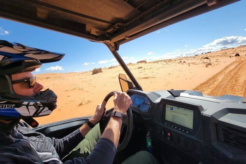 A vehicle driving on a sandy terrain with a clear sky. 2