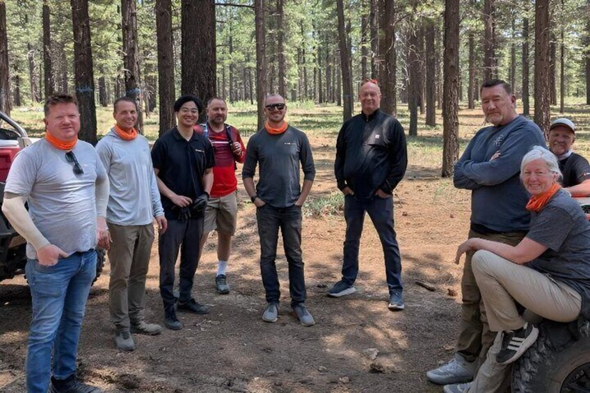 A group of people standing in a forested area with trees and a dirt path. 4