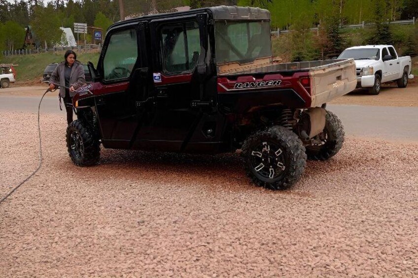 A black off-road vehicle with large tires parked on gravel. 5