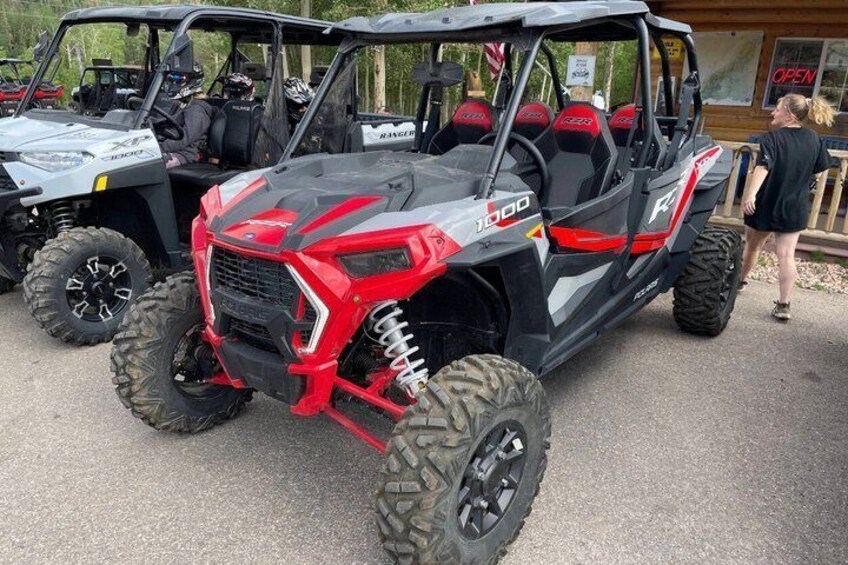 A red and black off-road vehicle with large tires and a high ground clearance. 3