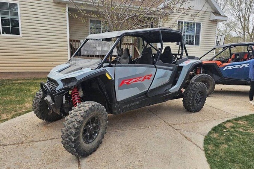 A Polaris RZR off-road vehicle parked in front of a house. 1