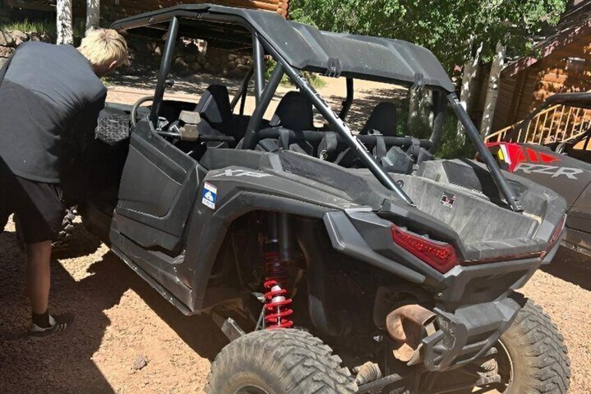 A black off-road vehicle with a visible spare tire and a red recovery jack. 2