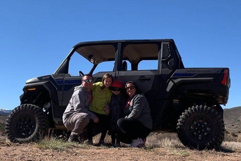 A group of people posing with a black off-road vehicle in a natural landscape. 5