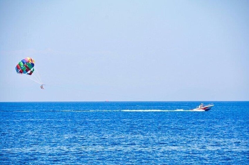 Un parasailista sobre el océano, con un velero a motor en el fondo. 2