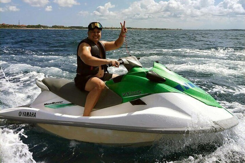 Una persona conduciendo un jet ski Yamaha sobre aguas claras, con cielo despejado y una costa lejana. 1