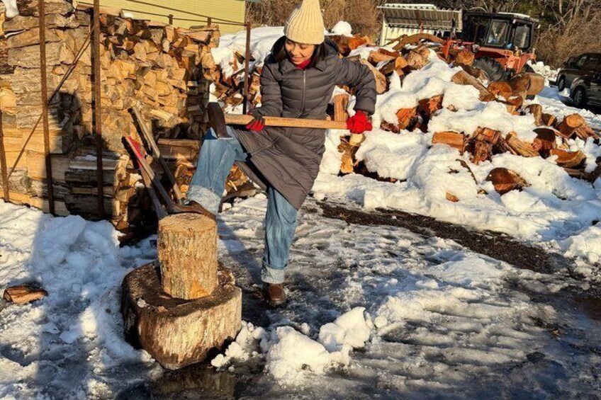 A person chopping wood with an axe near a stack of firewood. 5