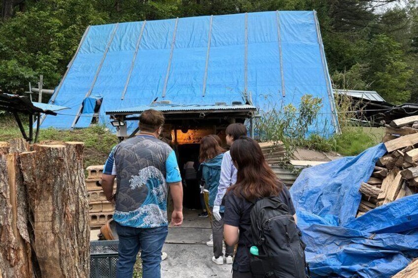 A group of people exiting a blue-roofed building with wooden planks and tarps around. 2