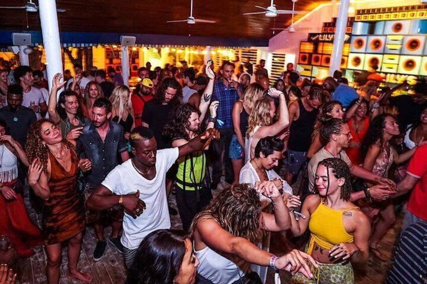 A crowded indoor social event with people dancing and interacting. 2