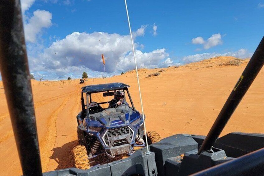 A blue off-road vehicle on a sandy terrain with a clear sky. 3