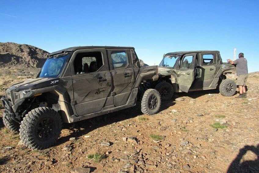 Two off-road vehicles on a rocky terrain with a clear sky. 1