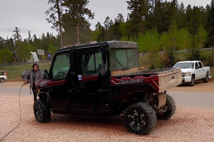 A red DAKINEAR off-road vehicle with a spare tire mounted on the back, parked on a gravel surface. 2