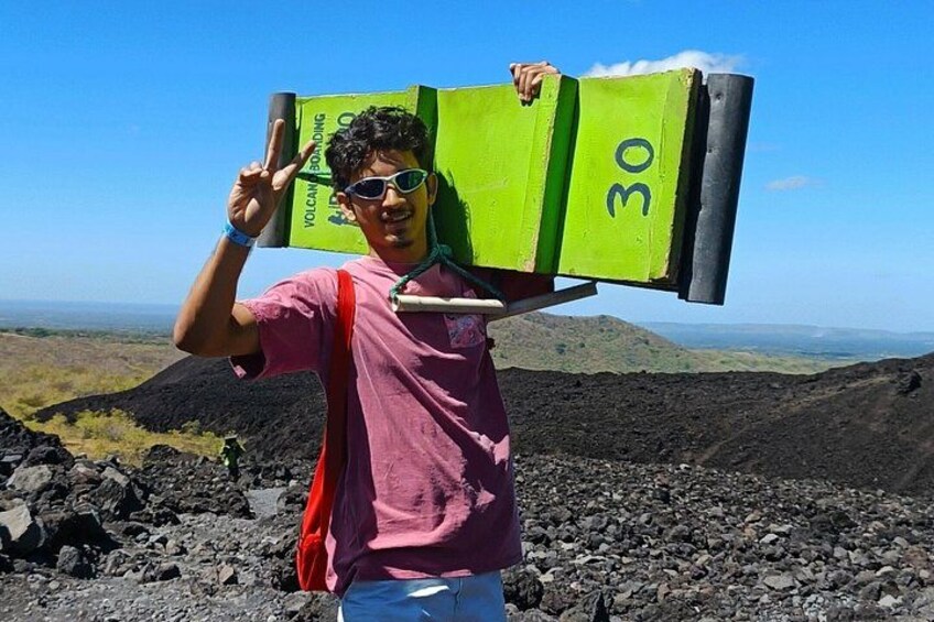 A person carrying a green box with the number 30 on it, standing on a rocky terrain with a clear sky. 3