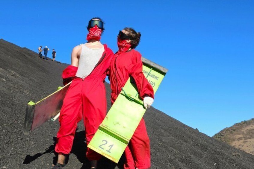 Two individuals in red protective suits carrying a green container marked with the number 21. 3