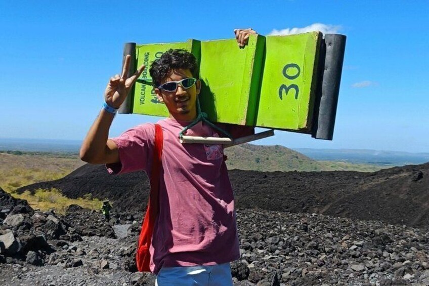 A person carrying a green object with the number 30 on it, standing on a rocky terrain with a clear sky. 4