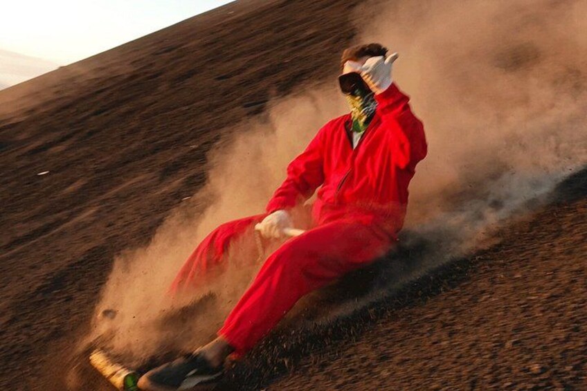 A person in a red suit sitting on a hill with dust around them. 1
