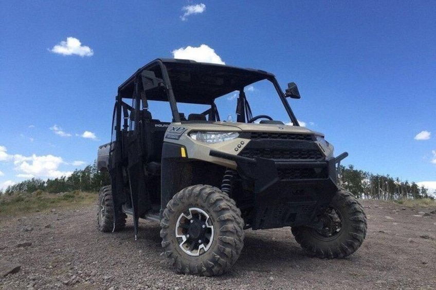 A utility vehicle on a dirt path with a clear sky. 1