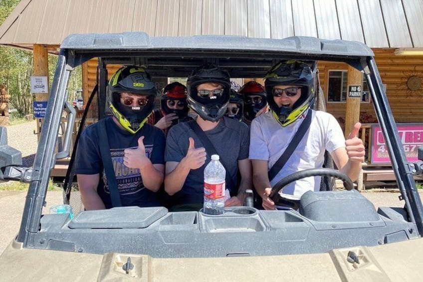 A group of people in a golf cart with helmets, thumbs up gestures, and a bottle of water. 4