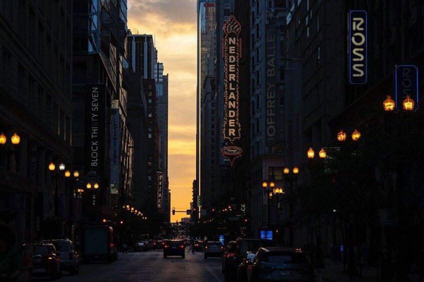 A city street at dusk with illuminated signs, including 'NEDERLANDER' and 'ROSS.' 3