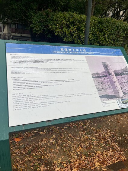 A historical marker detailing the hypocenter of the atomic bomb explosion, surrounded by trees and fallen leaves. 4