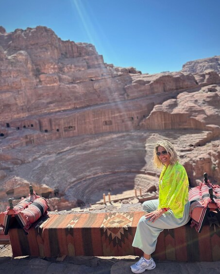 A person sitting on a patterned bench in a desert canyon with rock formations in the background. 3