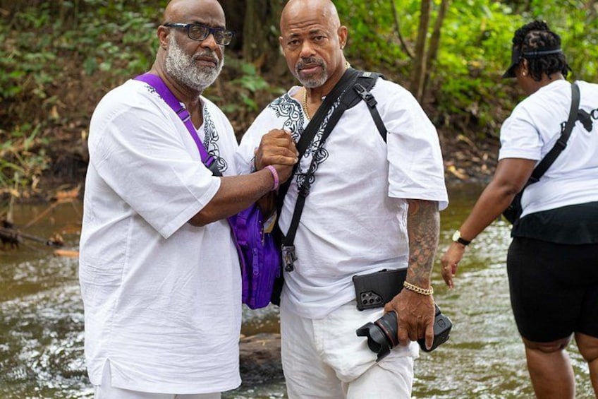 Two men in white shirts standing by a river. 1