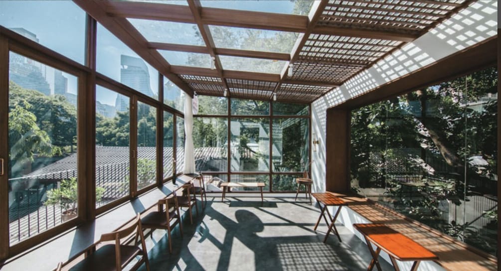 A conservatory with large windows, wooden furniture, and a view of a cityscape and greenery. 5