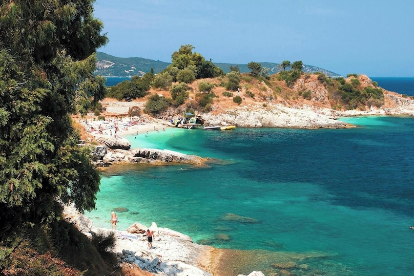 Une plage côtière bordée d’une eau turquoise et limpide, avec un terrain rocheux et une végétation clairsemée. 5