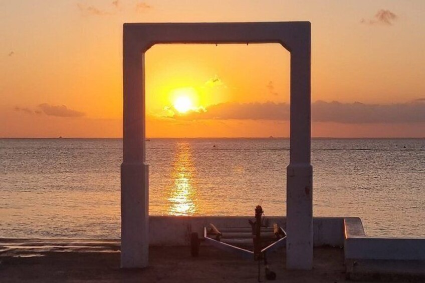 A sunset over the ocean with a concrete structure framing the view. 1