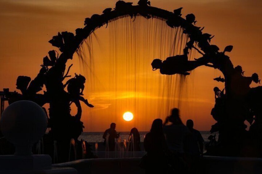 A sunset with silhouettes of people and a decorative arch. 5