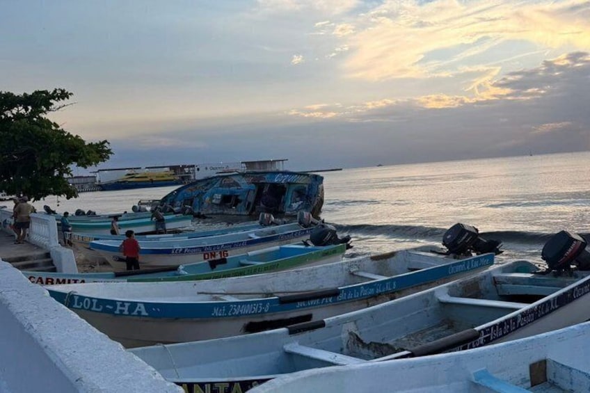Several boats docked at a pier with a calm sea and a sunset in the background. 4