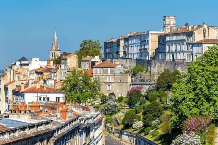 A historic town with old buildings, a church spire, and a well-maintained garden. 1