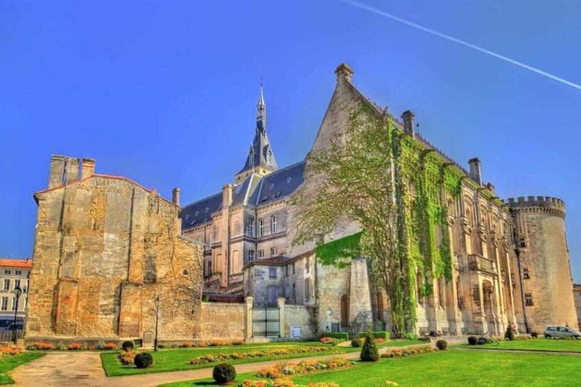 A historic building with a prominent tower, a large courtyard with a fountain, and a well-maintained garden. 4