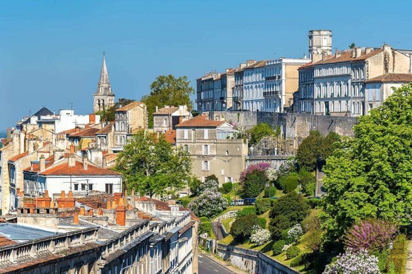 A historic town with old buildings, a church spire, and lush greenery. 1
