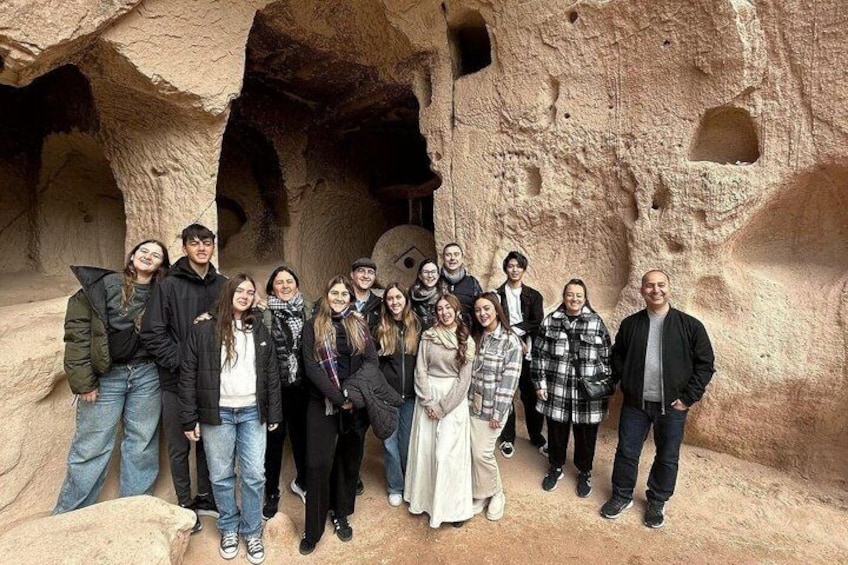 A group of people standing in a cave with natural rock formations and openings. 2